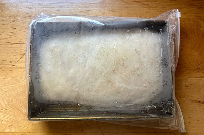 A 9x13-inch pan filled with cinnamon-sugar focaccia, tucked inside a 2-gallon ziptop bag.