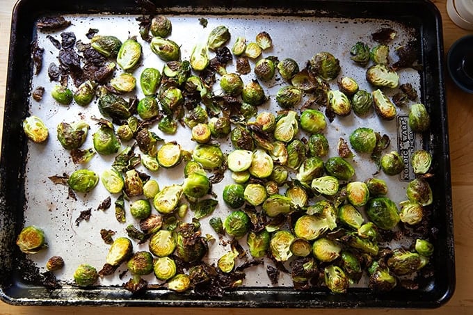 A sheet pan filled with roasted Brussels sprouts on a countertop.