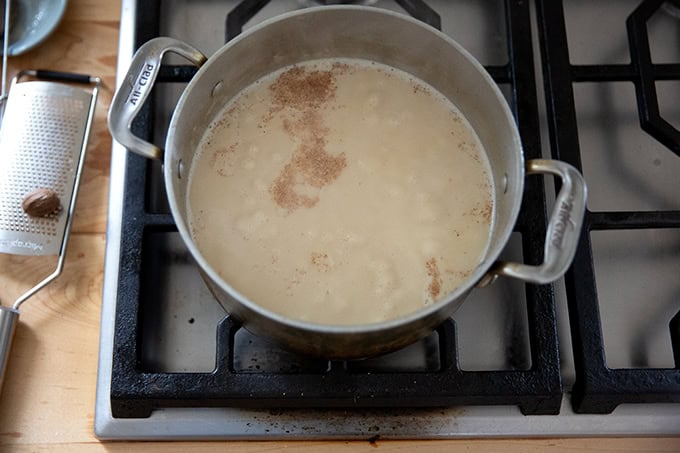 The gravy/bechamel sauce for turkey tetrazzini simmering on the stovetop with nutmeg added.
