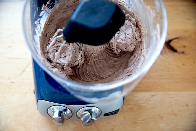 A stand mixer beating together chocolate cream cheese frosting.