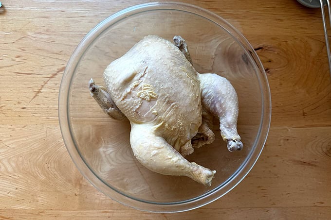 A whole chicken after an hour of poaching in hot water.