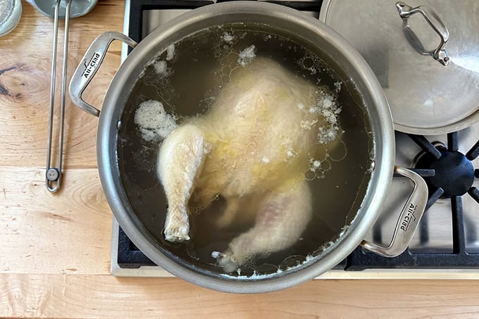 A large pot filled with a chicken after one hour of poaching.