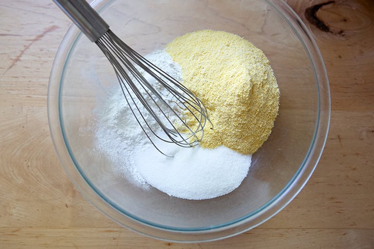 The dry ingredients to make cornbread in a large bowl with a whisk in it.