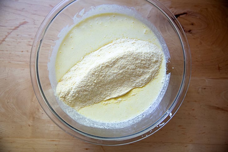 The dry ingredients to make cornbread added to the wet ingredients in a large bowl.