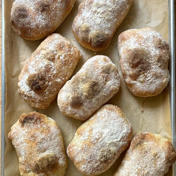 Eight just-baked Overnight Sandwich Rolls on a sheet pan.