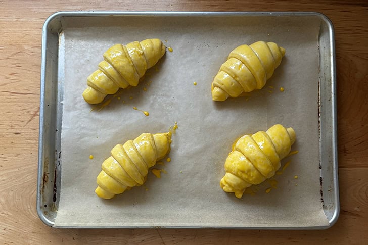 Four croissants, proofed and egg washed, ready for the oven.