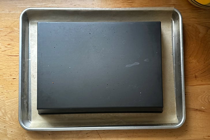 A turned over 10x14-inch pan on a sheet pan of proofing croissants.
