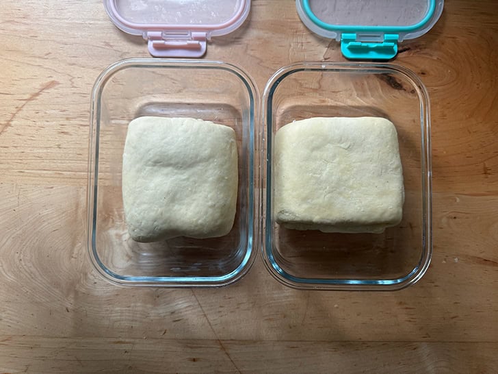 Two portions of croissant dough, each in a storage vessel.