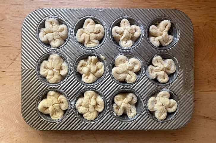 A muffin tin filled with unbaked Kouign-Amann.