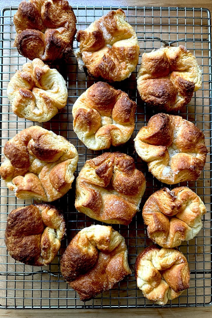 A dozen baked Kouign-Amann on a cooling rack.