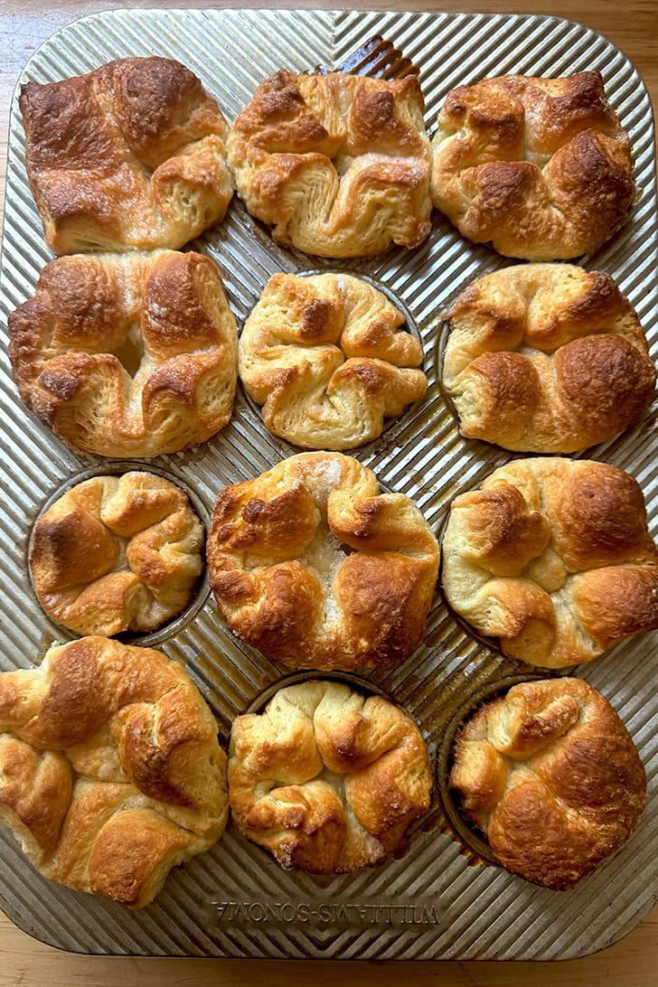 Just-baked Kouign-Amann in a muffin tin.