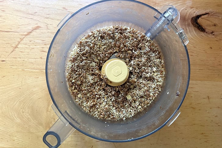 A food processor filled with puréed dates, oats, almonds, and coconut.