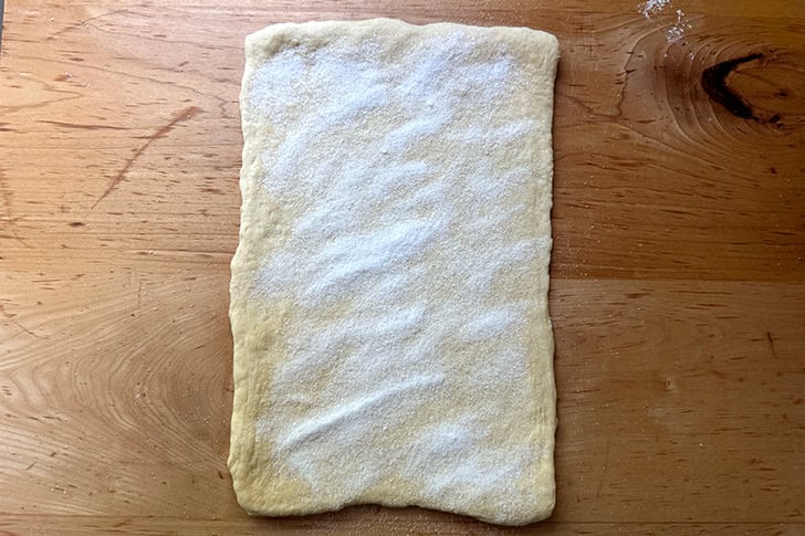 Kouign-Amann dough rolled into an 8x12-inch rectangle and sprinkled with sugar.